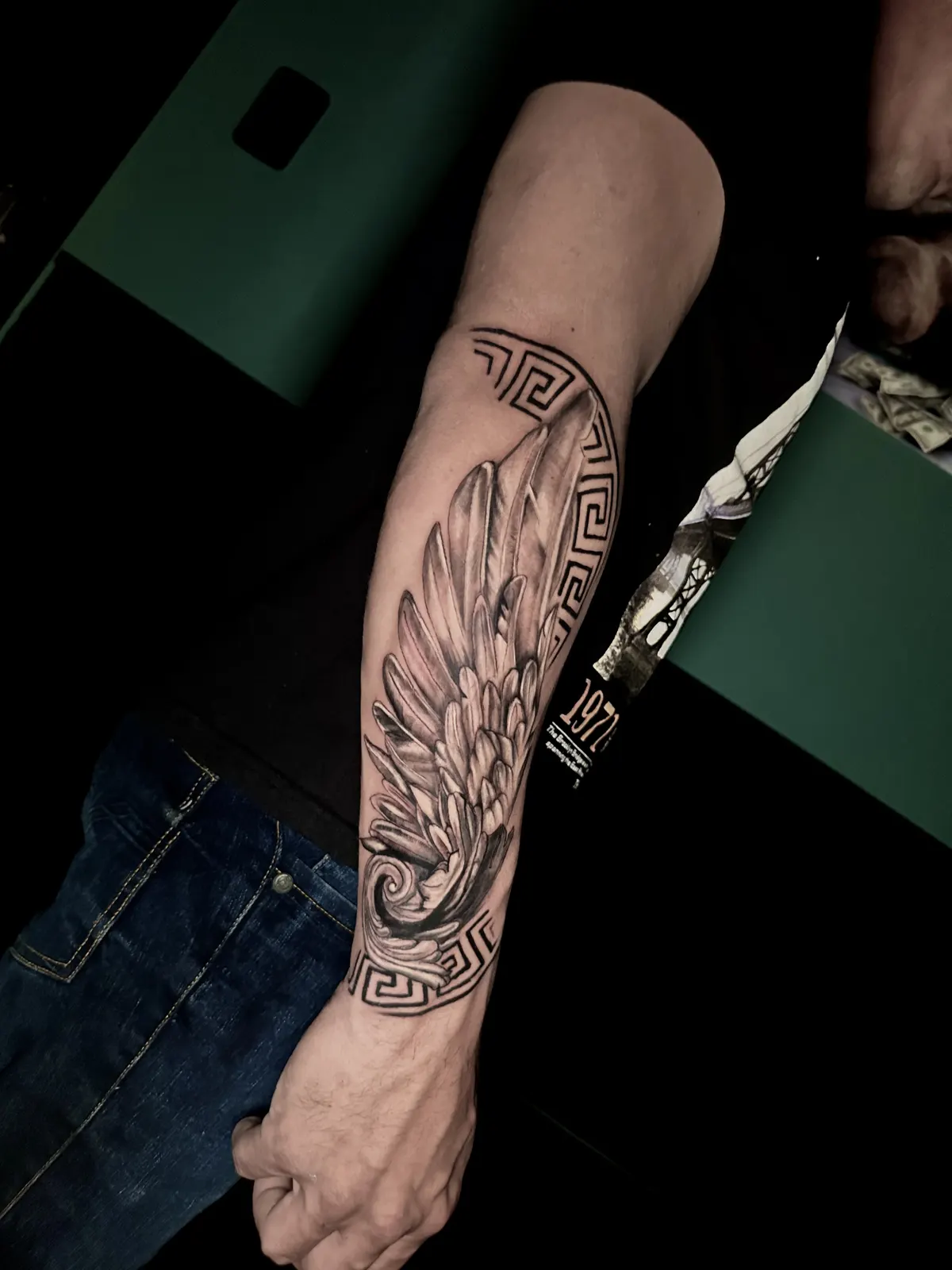 Tatuagem de asa de anjo no antebraço, com a composição chegando perto do pulso